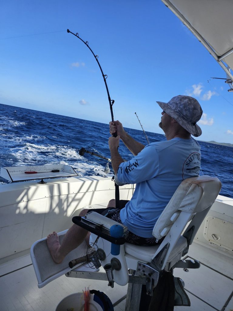 Angler in a fighting chair bends a heavy rod battling a big game fish offshore aboard the Fishtales Bonaire boat.