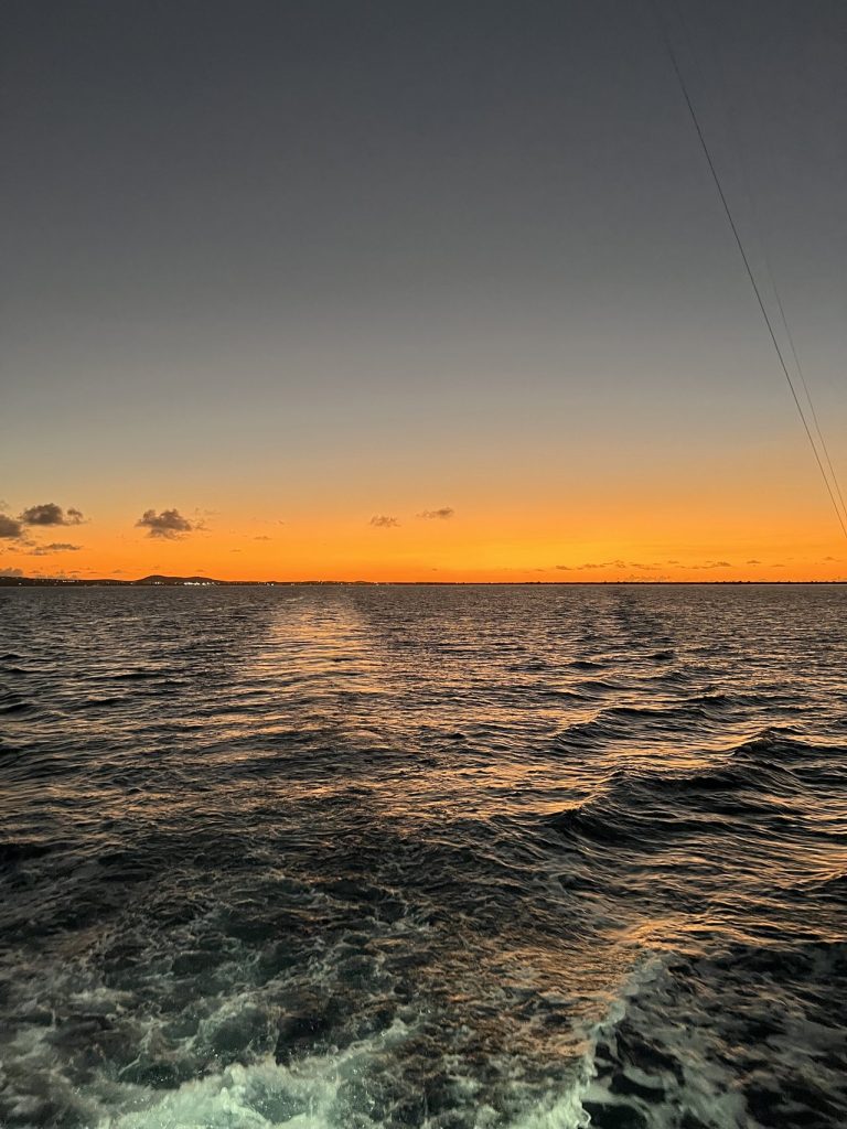 Vurige oranje zonsondergang aan de horizon boven de Caribische Zee gezien vanaf een Fishtales-visboot op weg terug naar Bonaire