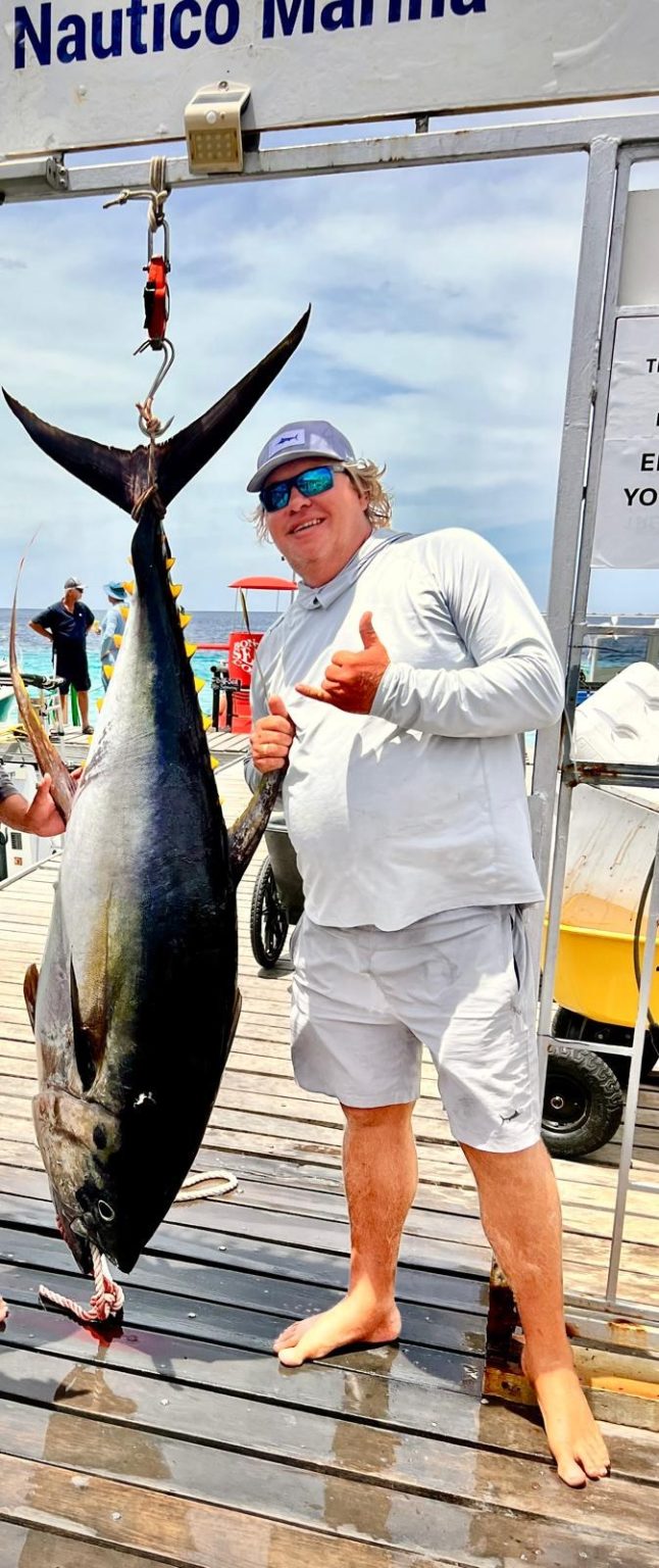 Captain Yuri of Fishtales Bonaire holding a large yellowfin tuna on the dock at Nautico Marina in Kralendijk, Bonaire