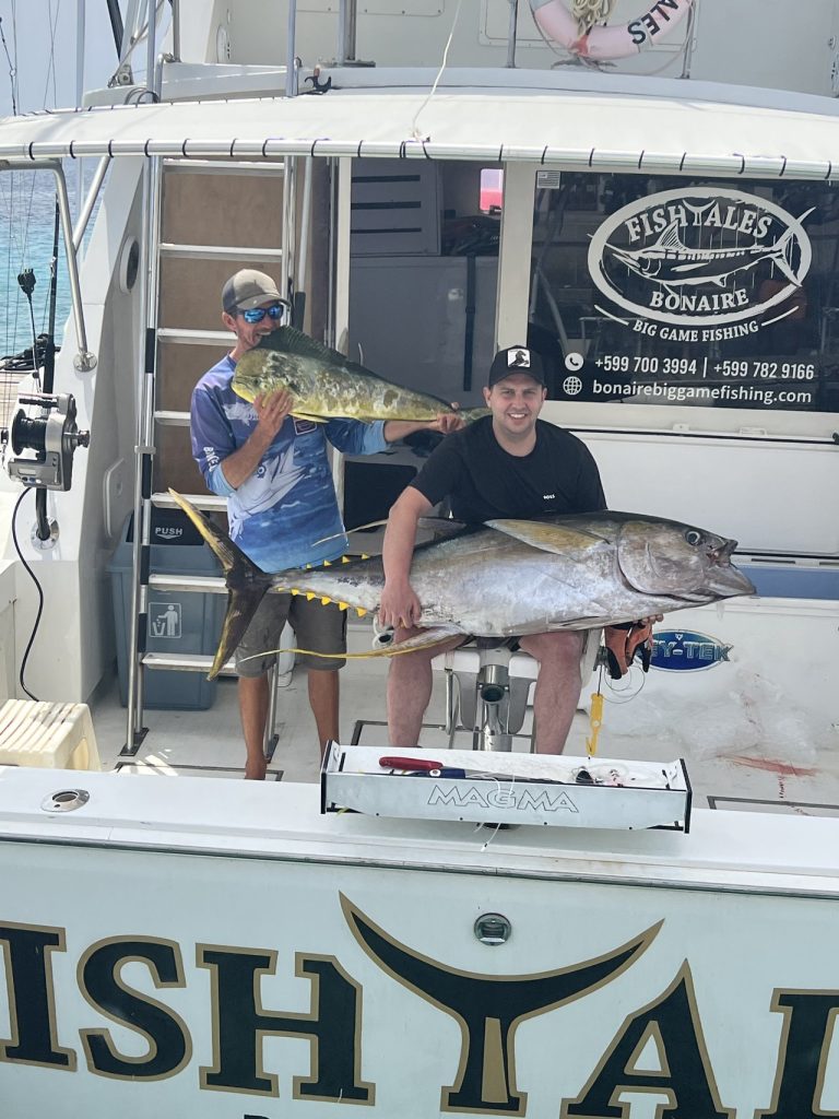 Visser met een enorme geelvintonijn terwijl een tweede visser een mahi-mahi vasthoudt op de Fish Tales Bonaire sportvisboot