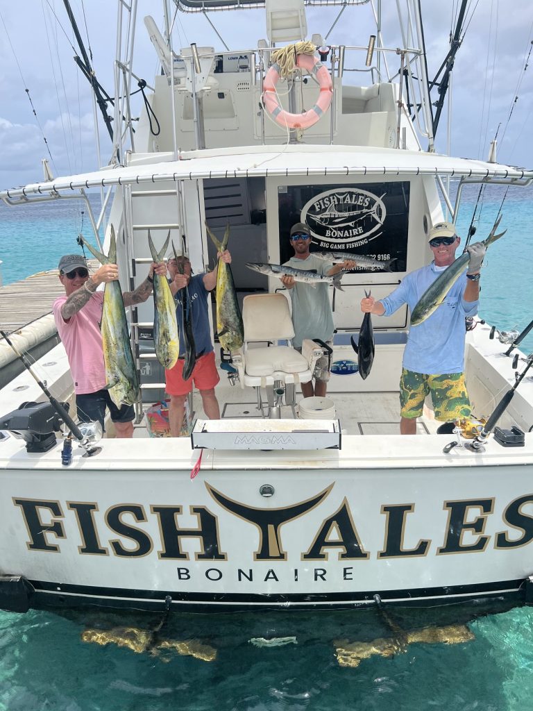 Drie vissers bij de achtersteven van de FISH TALES Bonaire boot met mahi-mahi, wahoo en tonijn na een big game fishing charter.