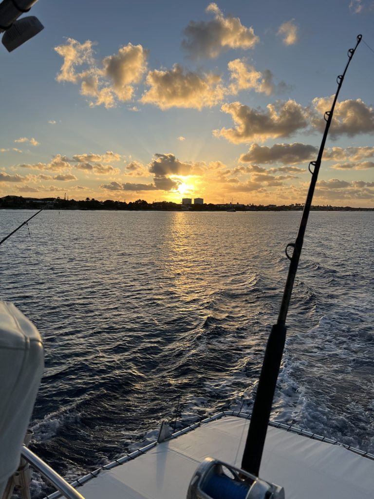 Golden sunrise over Bonaire seen past a trolling rod and reel on the deck of the Fishtales big game fishing boat.