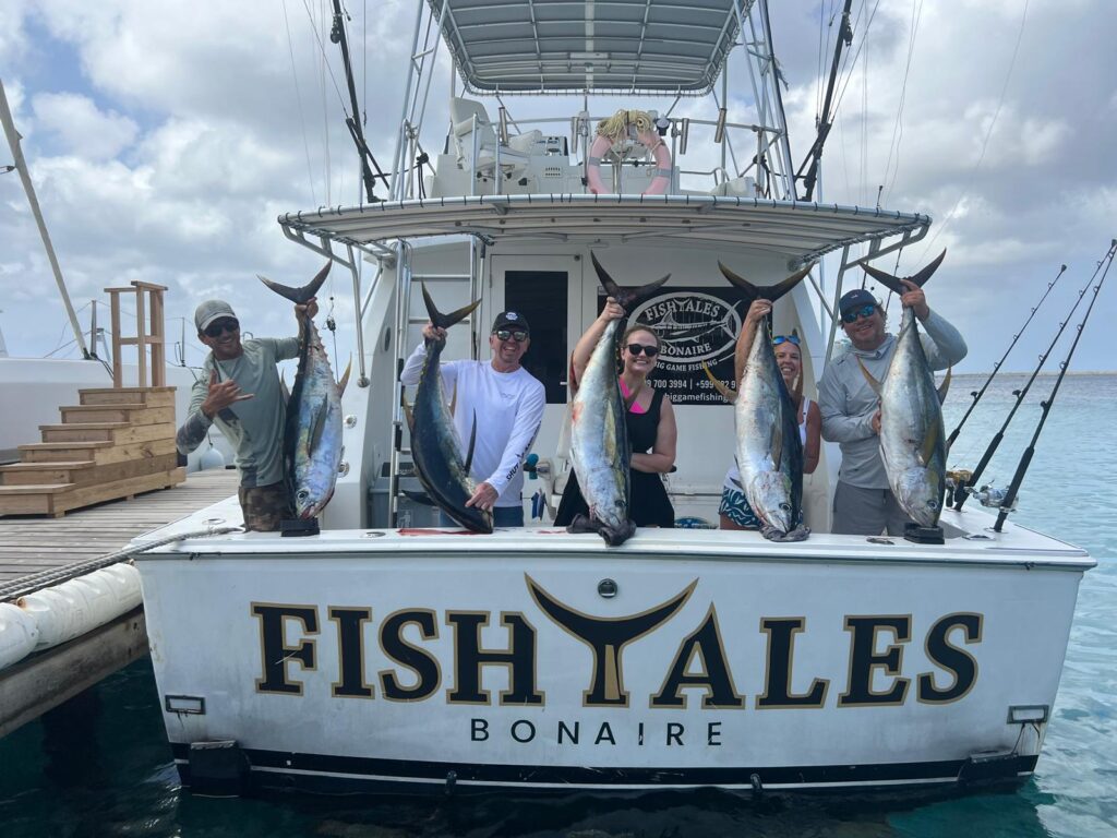 Fishtales Bonaire fishing charter guests holding five yellowfin tuna at the dock
